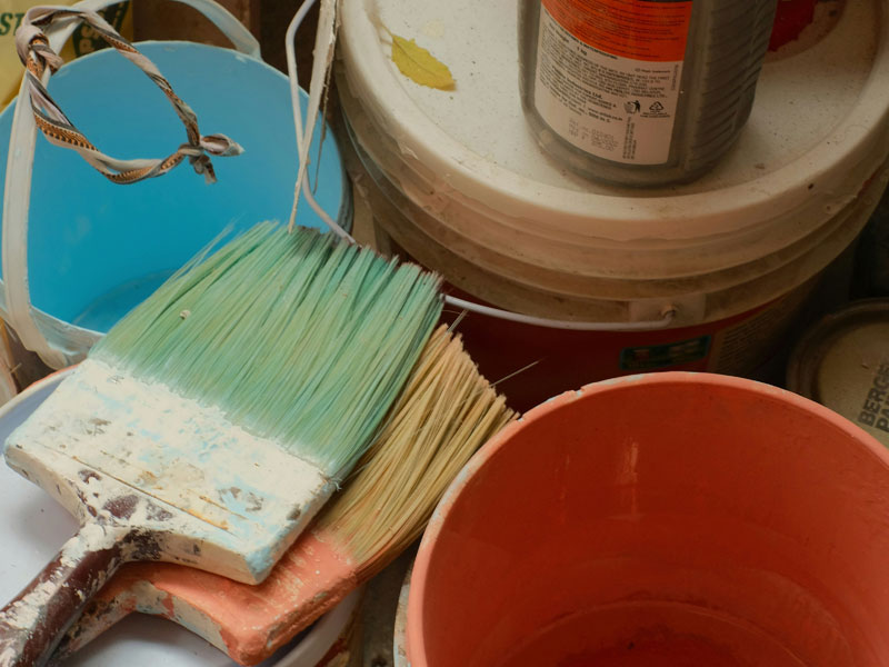Photo showing paint brushes and buckets of paint.